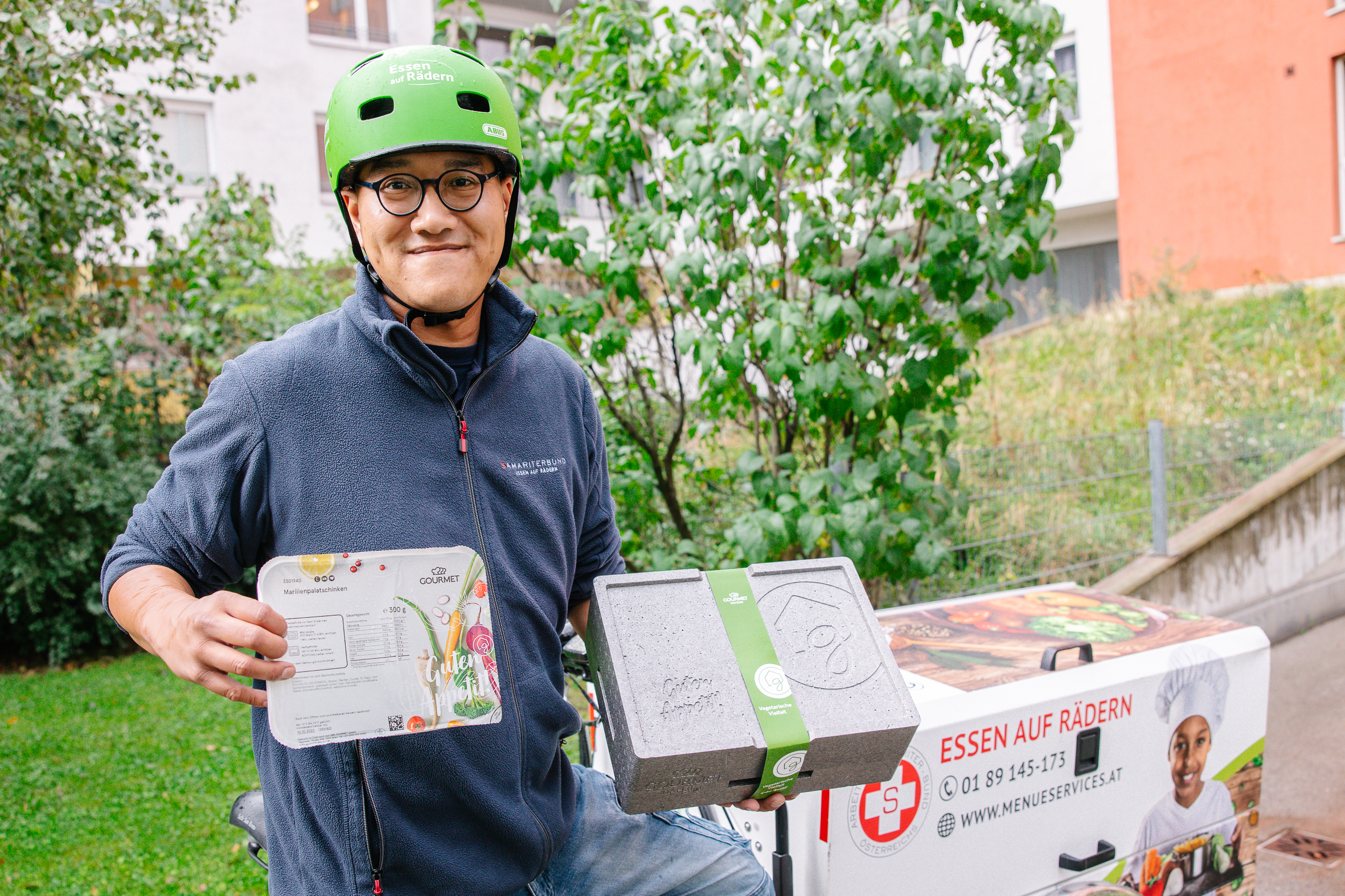 Zusteller vom Samariterbund mit GOURMET Speisen in der Hand